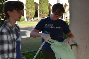 Two young guys proudly holding bags of trash, showing their commitment to keeping the area clean.